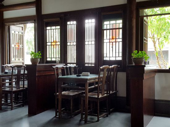 旅店在仓河北街的东头,仿古民居风格。门面不大,但进去后,大堂兼茶室,估计有七八十平米,临河而建,木质桌椅,装饰上透露着古风之意。想来在此喝喝茶、看看河、发发呆,一定很惬意的。进小镇后,可着沿河边,走仓河北街或仓河南街,一路往东,即可达客栈。客栈边上就是饭店,对面是土菜馆,东面边上是一家很不错的饭店。原订的是临河的观景标房,店家客气,免费升为临河观景套房,在二楼。房间很大,床边还有一沙发,可睡人,推窗见河,一株柳树,绿叶映窗,美且有意境。客栈的建筑是砖木结构,原木栋梁,有个漂亮的天井庭院,一汪池水,花盆盆景